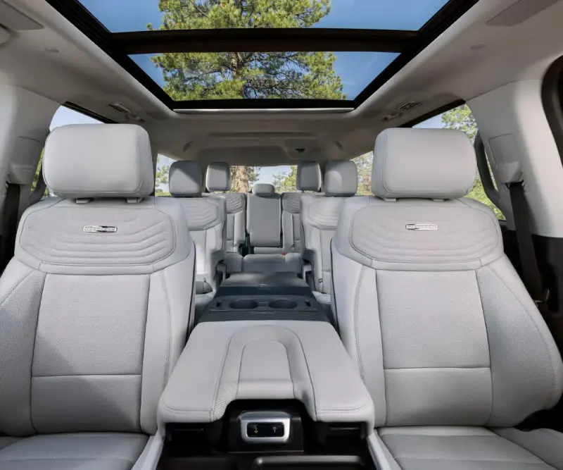 Light leather interior of a three-row executive SUV with a panoramic sunroof